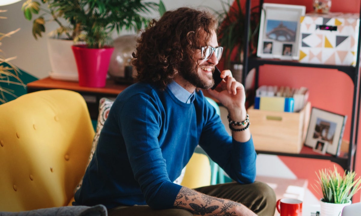 Remote worker on a living room chair talking on a mobile phone discussing top challenges for IT professionals in today’s hybrid environment